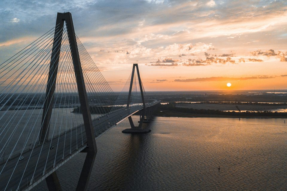 The Arthur Ravenel Jr. Bridge at sunset, carrying US-17 over the Cooper River between Mount Pleasant and downtown Charleston, with Daniel Island beyond.