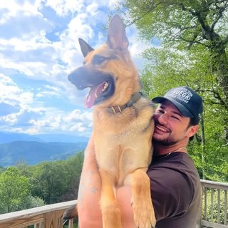 Harris Willburger, co-owner of Daniel Island Pet Waste Removal, holding his German Shepherd Breck.