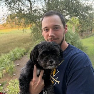 Shawn Runey, co-owner of Daniel Island Pet Waste Removal, holding his black terrier.